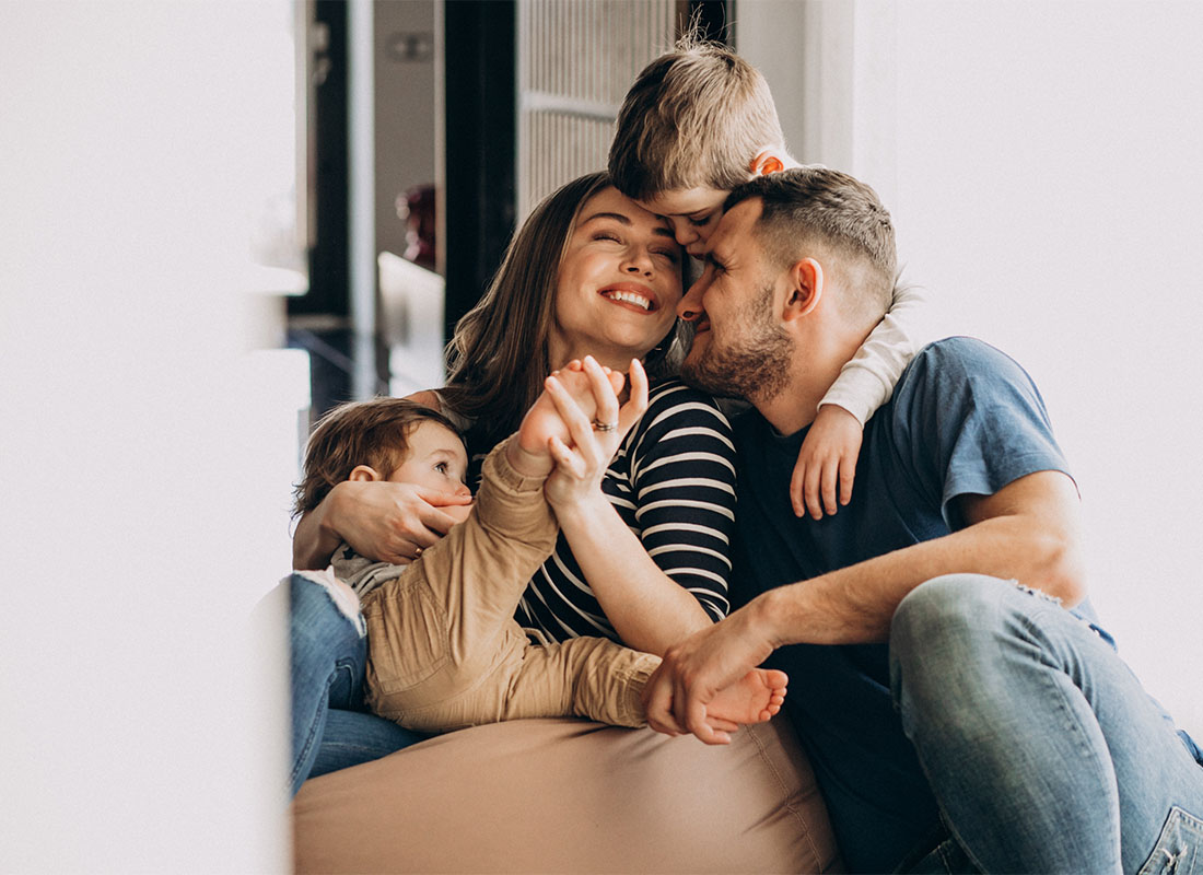 Personal Insurance - Portrait of a Happy Family with Two Young Children Having Fun Spending Time Together While Sitting in the Living Room
